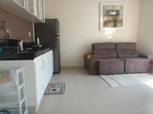 uma sala de estar com um sofá e uma cozinha em Apartamento para temporada em Vitória