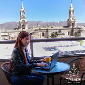 ARIQUEPAY HOTEL في أريكيبا: امرأة تجلس على طاولة مع جهاز كمبيوتر محمول
