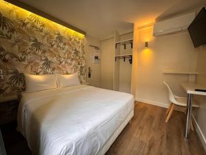 um quarto de hotel com uma cama, uma secretária e uma mesa em Hotel Nation Montmartre em Paris