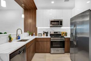 a kitchen with wooden cabinets and a stainless steel refrigerator at Exuberant King Bed Near EWR w/ Gym & Parking in Newark