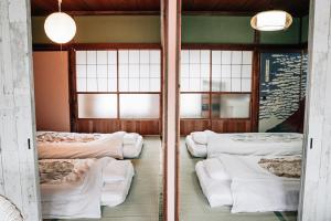小田原市にあるティピー レコーズ ハウスのベッド4台と窓2つが備わる客室です。