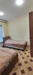 - une chambre avec 2 lits, une fenêtre et un sol dans l'établissement Pink Quest House, à Lankaran