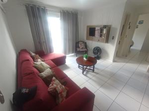 a living room with a red couch and a table at Apto espaçoso uma quadra do mar com garagem in Balneário Camboriú