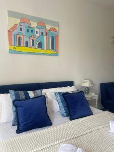 a bedroom with a bed with blue pillows and a painting at Villa Neptunus in Ischia