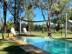 a swimming pool with two chairs and a hammock in a yard at Red Tractor Retreat in Broke