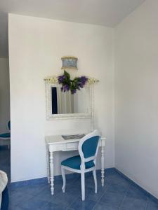 - un bureau blanc avec une chaise bleue et un miroir dans l'établissement Villa Neptunus, à Ischia