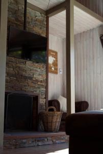 un soggiorno con camino in pietra e TV a schermo piatto di Chalet le Faye a Waimes