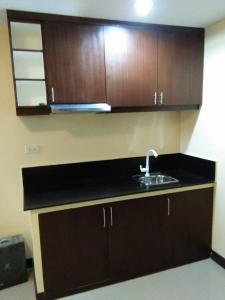 a kitchen with a sink and wooden cabinets at Argao Aballe Pension House/Apartelle in Argao