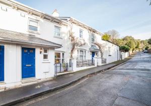 a row of white houses with blue doors on a street at Beach Mews in Torquay