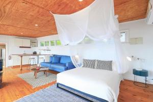 um quarto com uma cama branca e um sofá azul em Boatshed em Huskisson