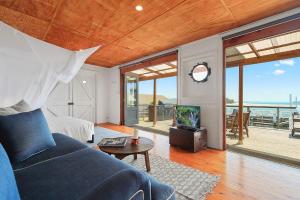 uma sala de estar com um sofá azul e vista para o oceano em Boatshed em Huskisson