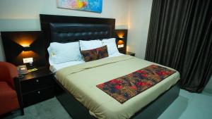 a bed in a hotel room with a red chair at The Lodge-Stack By Kabachi in Lagos