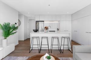 a kitchen with a counter and stools in a room at Elegant Inner-West 2-Bed with City Views & Pool in Melbourne