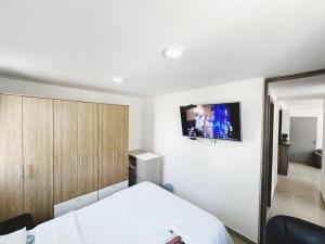 1 dormitorio con 1 cama y TV en la pared en Apt AA 15min CC B/Vista low cost, en Barranquilla