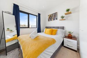Un dormitorio con una cama con almohadas amarillas y una ventana en OCEAN BLUEZ 1bdr city centre, en Hemel Hempstead