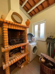 ein Wohnzimmer mit einem gemauerten Kamin und einer Waschmaschine in der Unterkunft Casa da Bivó in Figueiró dos Vinhos
