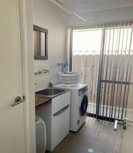 uma cozinha com uma máquina de lavar roupa e um lavatório em Halls Head Beach Haven em Mandurah