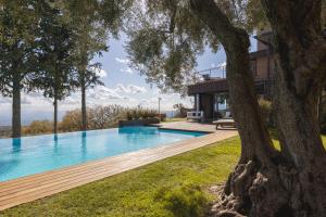 une maison avec une piscine et un arbre dans l'établissement Lussuosa Villa di Design in Sicilia con Piscina e Vista Mare Relax e Comfort a 5 stelle, à Ragalna