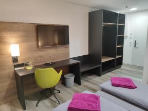 ein Schlafzimmer mit einem Schreibtisch und einem gelben Stuhl in der Unterkunft Hotel Gästehaus Stock Zimmer Bäumle in Friedrichshafen