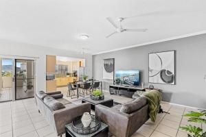 a living room with two couches and a flat screen tv at Cairns City Apartments in Cairns
