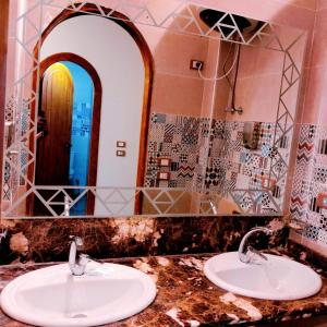uma casa de banho com dois lavatórios em frente a um espelho em New Abusimble 2 Hotel & Restaurant em Abu Simbel