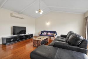 a living room with a couch and a tv at Matipo Retreat - Christchurch Holiday Home in Christchurch
