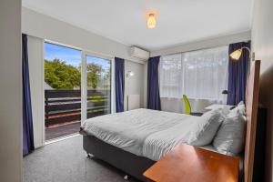 a bedroom with a bed and a large window at Matipo Retreat - Christchurch Holiday Home in Christchurch