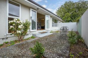 a home with a patio with a chair in the yard at Matipo Retreat - Christchurch Holiday Home in Christchurch