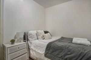 a white bedroom with a bed and a night stand at Cozy 1-Bed Apartment Close to Lcy & Excel in London