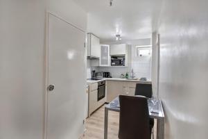 a kitchen with white cabinets and a table and chairs at Cozy 1-Bed Apartment Close to Lcy & Excel in London