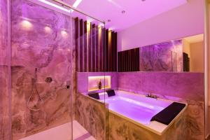 een paarse badkamer met een bad en een douche bij AlbaDea Déco&Jacuzzi in Rome