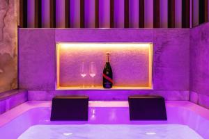 eine lila Badewanne mit einer Flasche und zwei Gläsern in der Unterkunft AlbaDea Déco&Jacuzzi in Rom