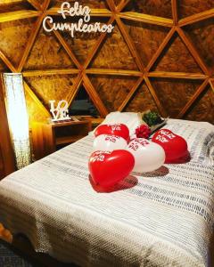 a bed with three red pillows on top of it at Huna Glamping in Guatavita