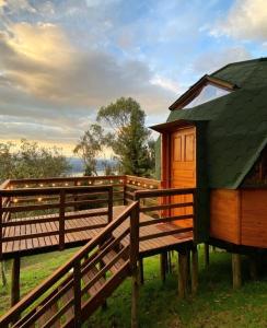 a wooden cabin with a green roof next to a fence at Huna Glamping in Guatavita