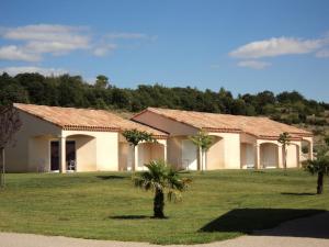 ein Haus mit zwei Palmen auf einem Feld in der Unterkunft Park & Suites Village Gorges de l'Hérault-Cévennes in Brissac