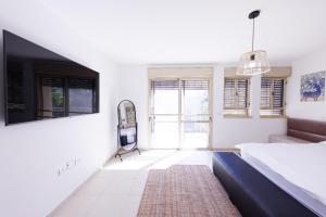 1 dormitorio con 1 cama y TV en la pared en Large house with a Great Deal ! en Hod HaSharon