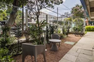 a garden with chairs and a table and trees at Valpi NB Living in Porto Alegre