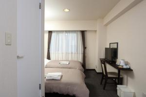 札幌市にある札幌オリエンタルホテルのベッド、デスク、テレビが備わるホテルルームです。