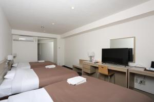 Habitación de hotel con 2 camas y escritorio con TV. en Sapporo Oriental Hotel, en Sapporo