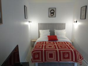 a bedroom with a bed with a red blanket on it at Studio Zoé in Saint-Père