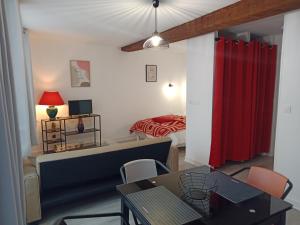 a living room with a red curtain and a bedroom at Studio Zoé in Saint-Père