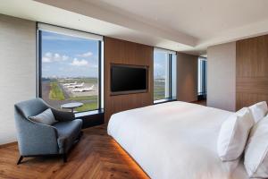 a bedroom with a bed and a chair and a television at Hotel Metropolitan Tokyo Haneda - 2023-10-17 Grand Opening in Tokyo