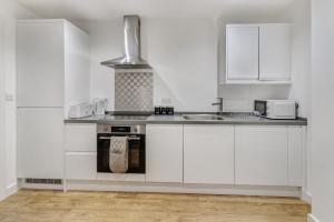 Una cocina blanca con gabinetes blancos y un fregadero. en 1 Bed Sleeps 3 Free Parking Wifi, en Slough