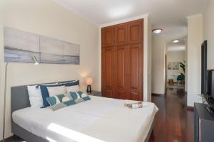 ein Schlafzimmer mit einem großen weißen Bett mit blauen Kissen in der Unterkunft Apartamento do Carmo by An Island Apart in Funchal