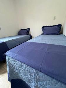 - 2 lits dans une chambre avec des draps et des oreillers violets dans l'établissement Sobrado bem próximo ao Aeroporto, à Guarulhos