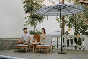 een man en vrouw die op stoelen zitten onder een paraplu bij Casa Asturias in Ensenada