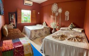 two beds in a room with red walls at Vila icarai in Caucaia