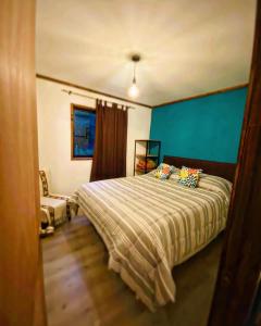 1 dormitorio con cama y pared azul en Cabañas Los Glaciares, en Coñaripe