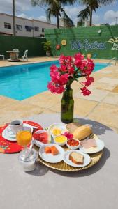 una mesa con platos de comida y un jarrón con flores en Vila icarai en Caucaia