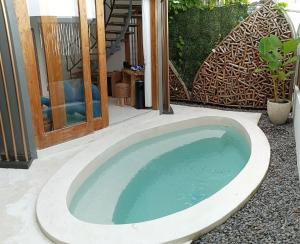 a jacuzzi tub in a yard with a chair at Sangkar Cottage & Eatery in Yogyakarta